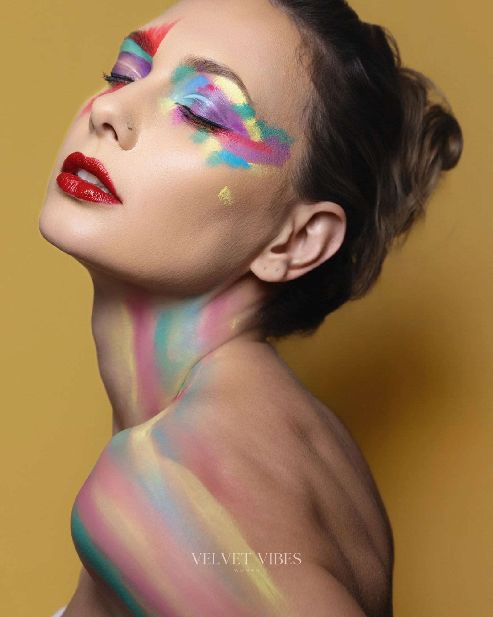 Olesia Prodan wearing vivid rainbow body paint against a gold background