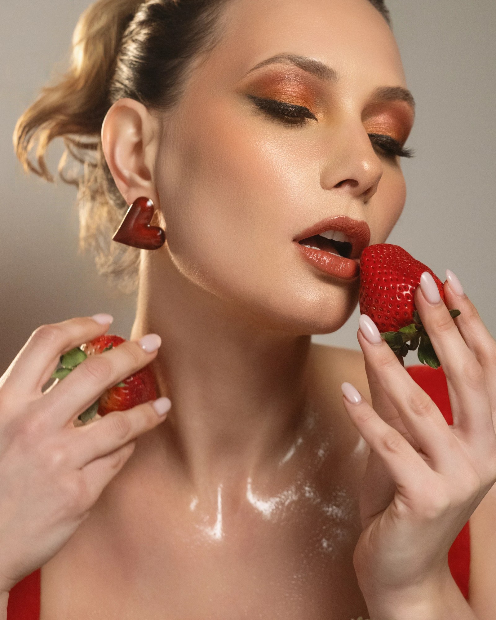 Beauty portrait of Olesia Prodan with strawberries and warm red makeup