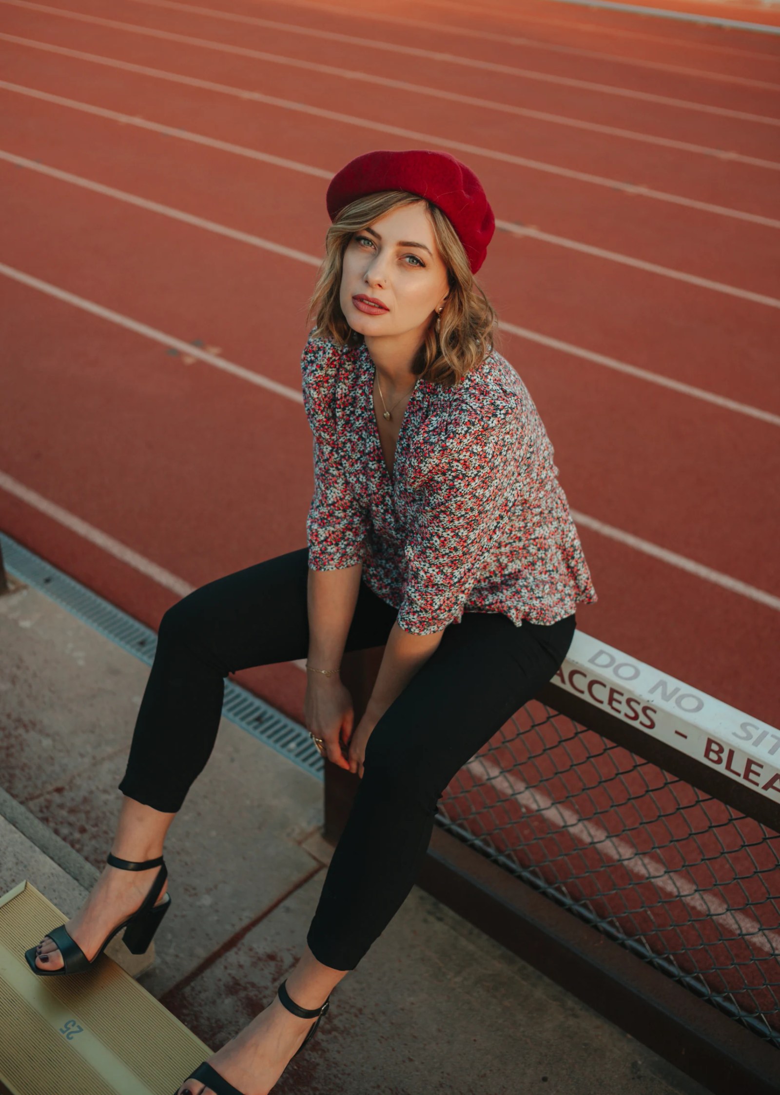 Olesia Prodan in a red beret and patterned blouse beside a running track