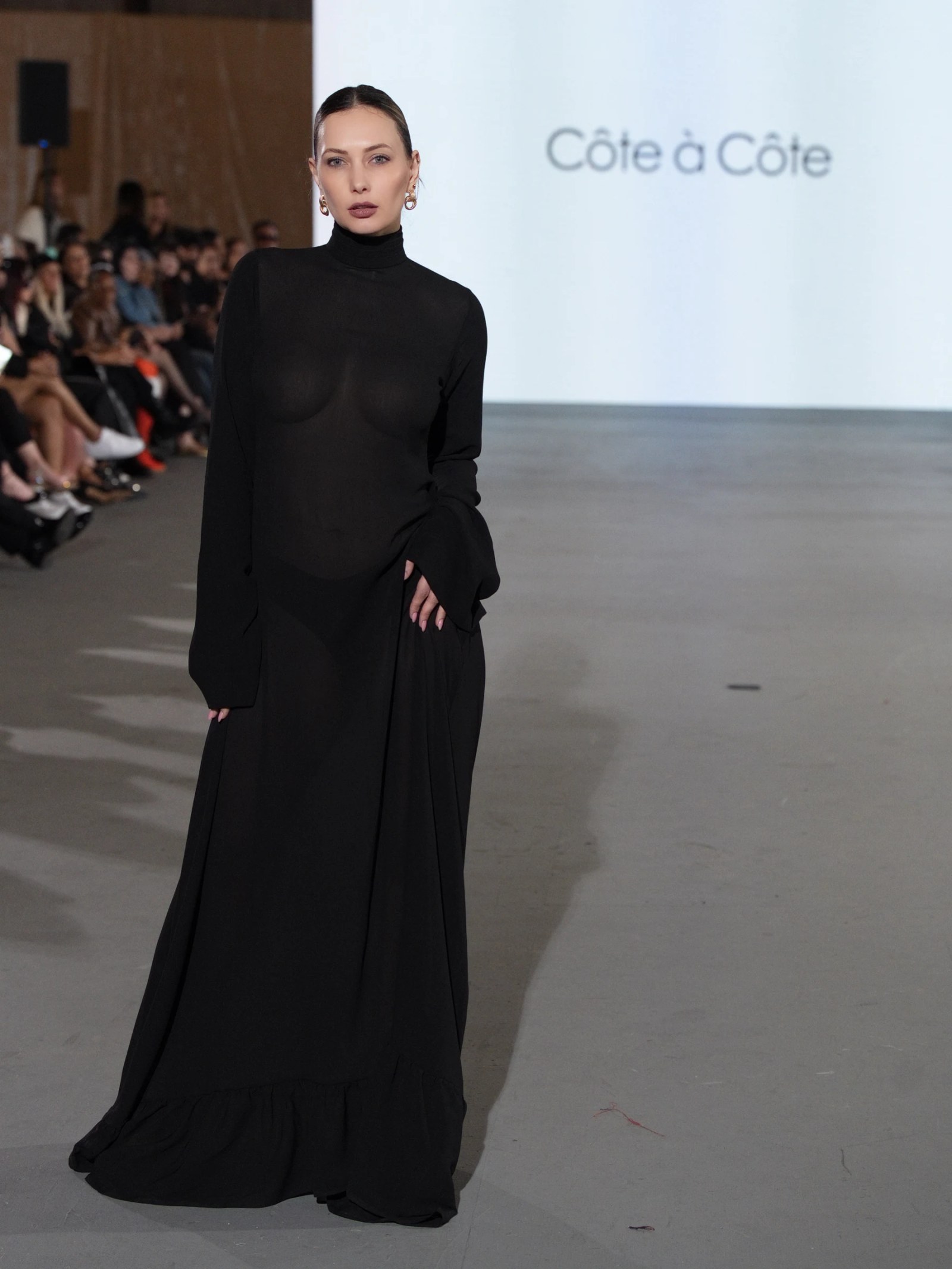 Olesia Prodan walking the runway in a sculptural floor-length black gown
