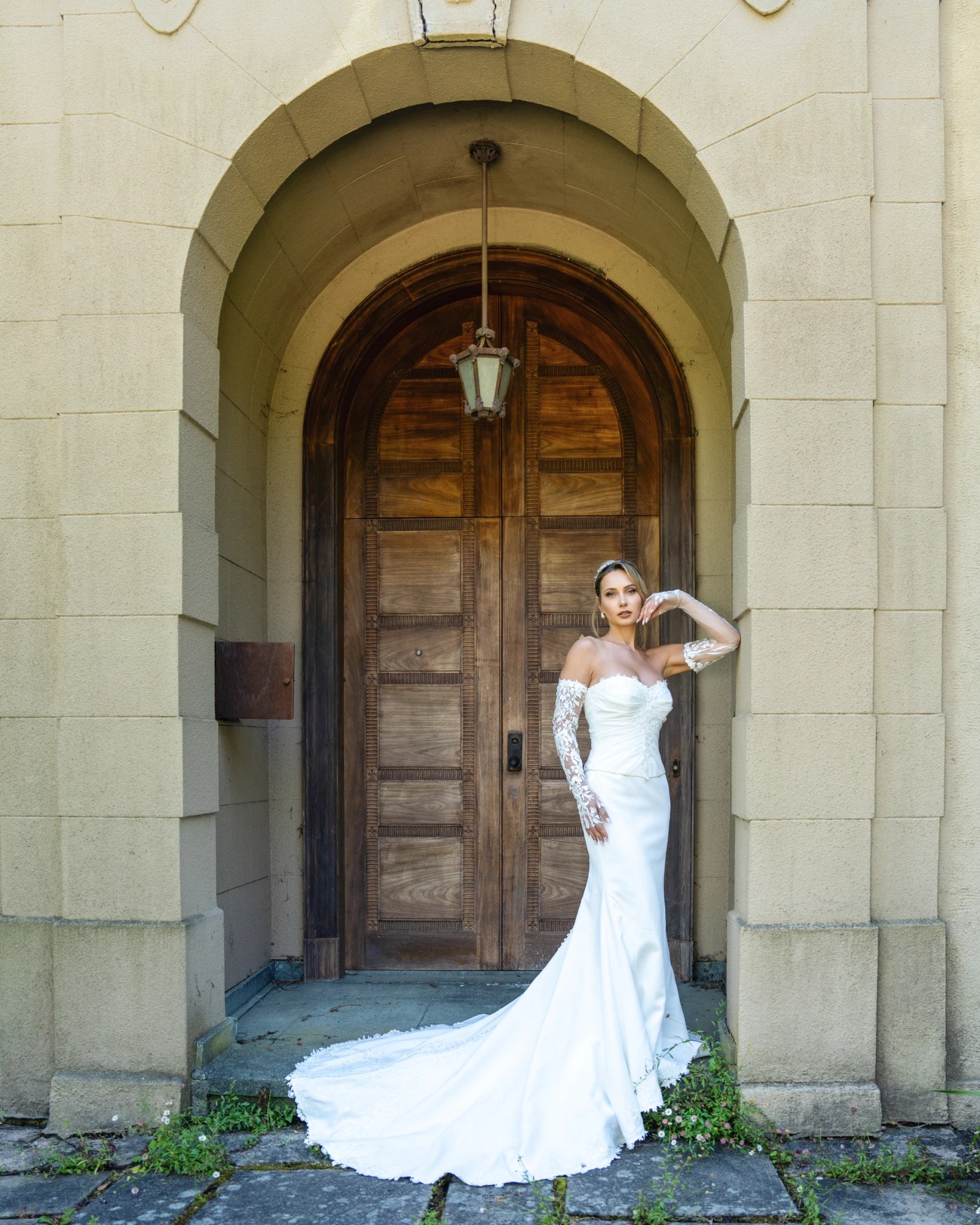 Olesia Prodan in a fitted white wedding gown beneath a stone archway