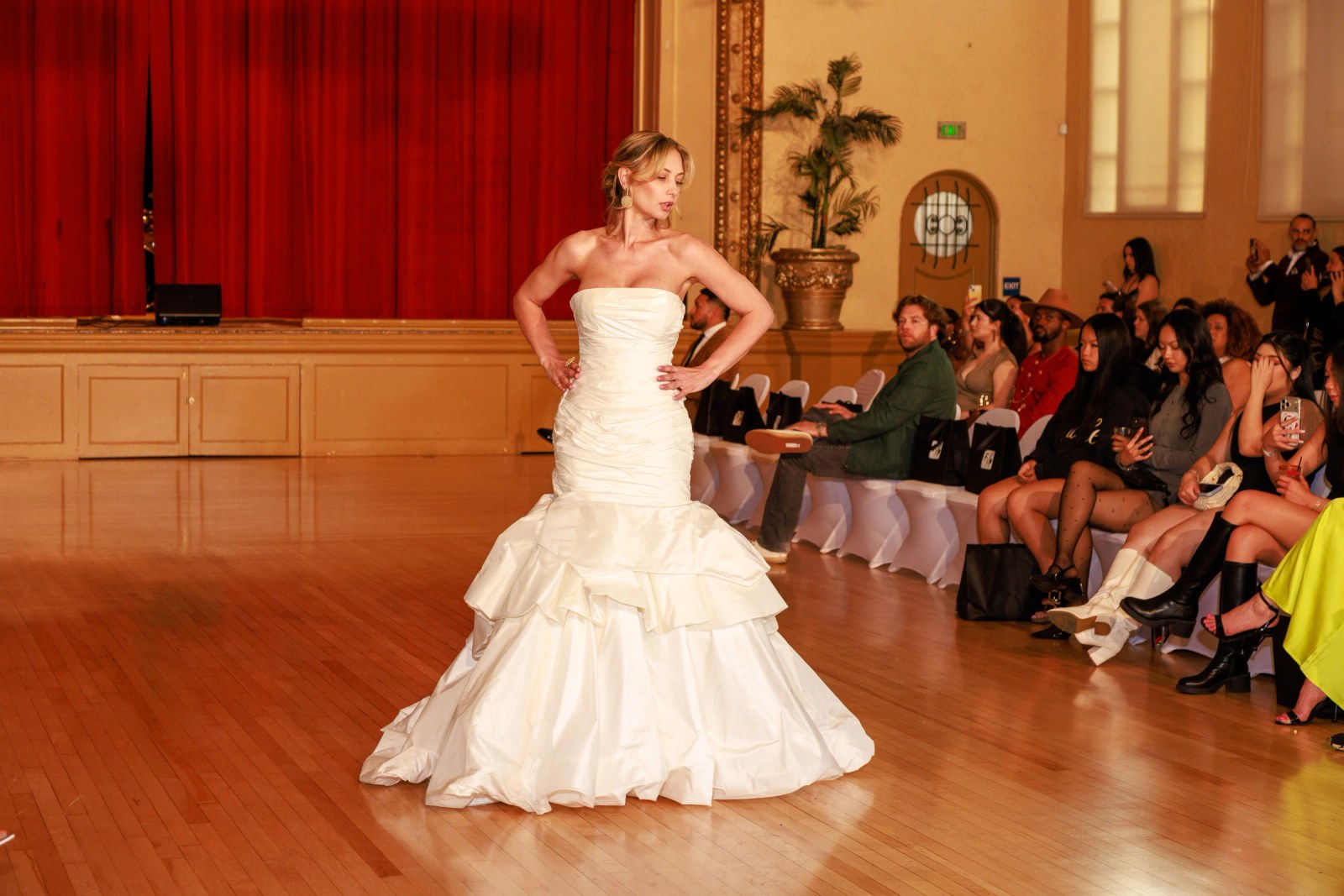 Olesia Prodan presenting a white wedding gown at a bridal runway show